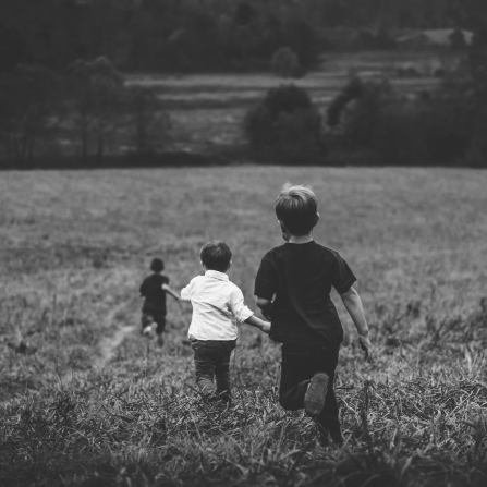 Three kids running down a hill.